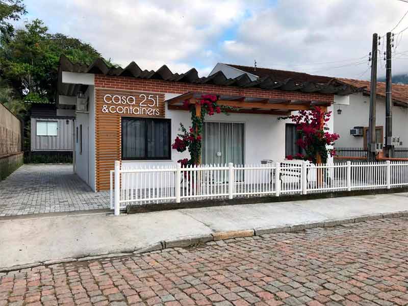 Entrada da Casa 251 com flores e porta de vidro