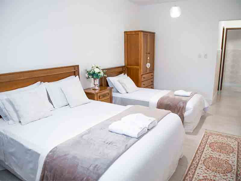 Quarto da Casa Branca com cama de casal e cama de solteiro e guarda-roupa de madeira ao lado