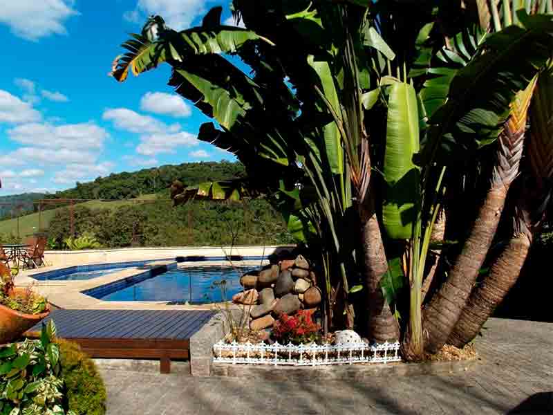 Área externa da Casa Branca, dica de pousada em Pomerode, com piscina e jardim em dia de céu azul