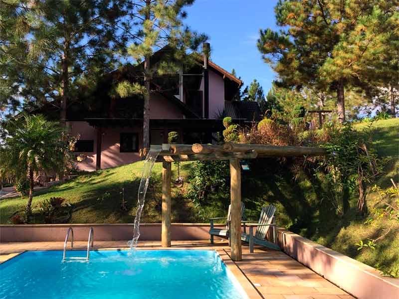 Piscina vazia e área externa do Casarão Gastehaus, dica entre as pousadas em Pomerode, com jardim em dia de céu azul