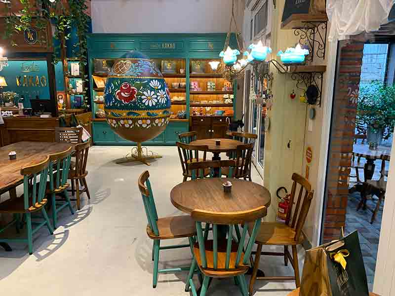 Parte interna da loja Feito Kakao com ovo de Páscoa gigante e mesas e cadeiras vazias