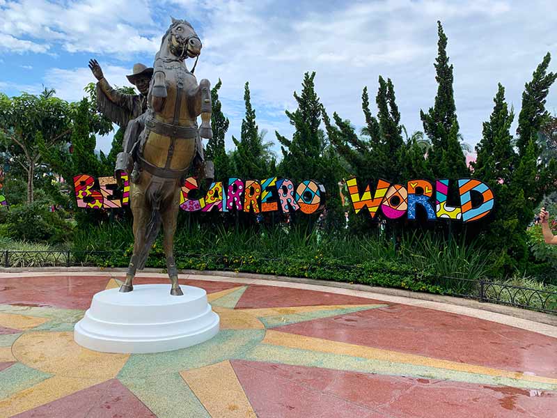 Estátua do Beto Carrero e seu cavalo com logo atrás com artes do Romero Britto e árvores