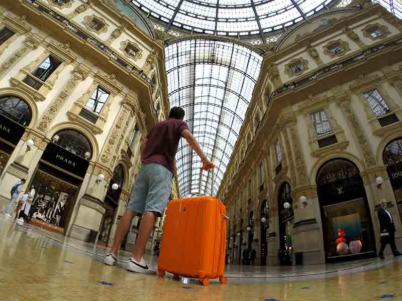 Homem de costas em pé com mala laranja na Galleria Vittorio Emanuele II em Milão