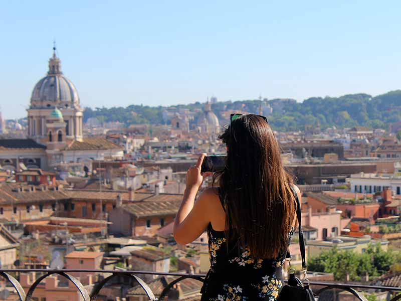 Menina de costas tira foto com celular de vista panorâmica de Roma