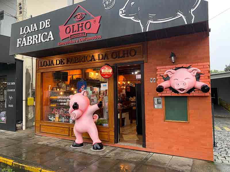 Porquinho na entrada da loja de fábrica da Olho Embutidos em dia de chuva