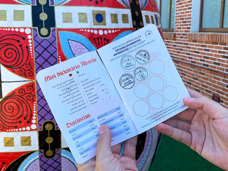Pessoa mostra o passaporte turístico de Pomerode com alguns carimbos