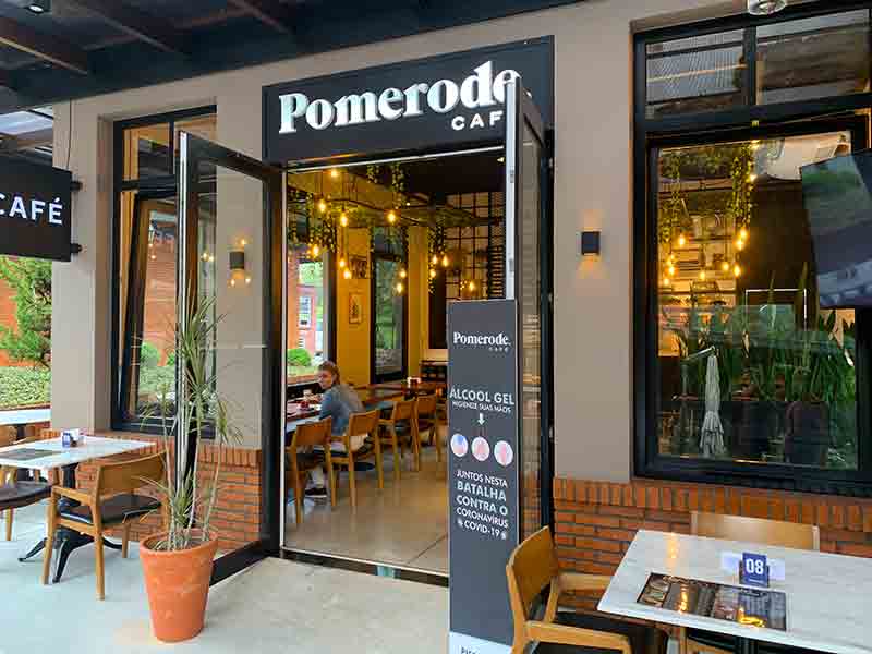 Entrada do Pomerode Café, dica do que fazer em Pomerode, com pessoa sentada em mesa tomando café