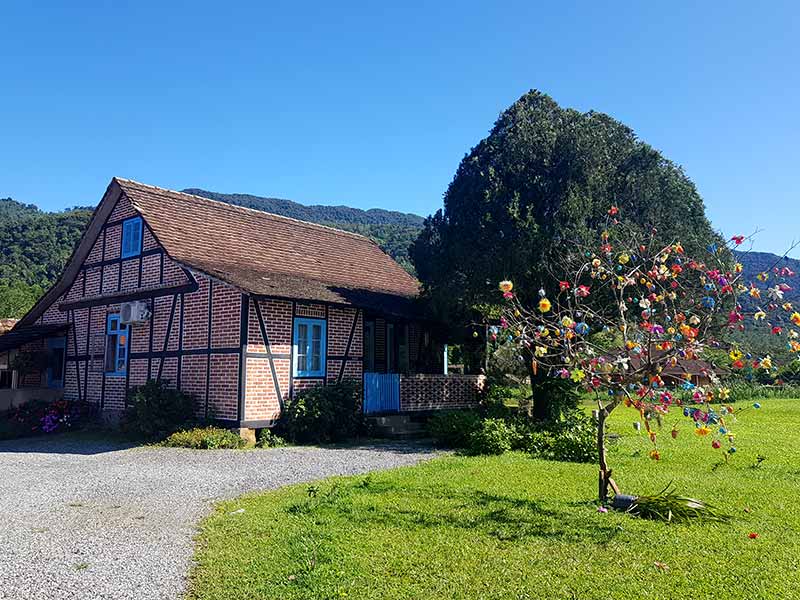 Casa enxaimel com gramado e árvore com ovos coloridos em Pomerode, Santa Catarina