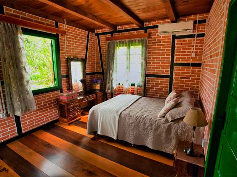 Quarto da Pousada do Imigrante, dica entre as pousadas em Pomerode, em estilo Enxaimel com cama de casal e piso de madeira