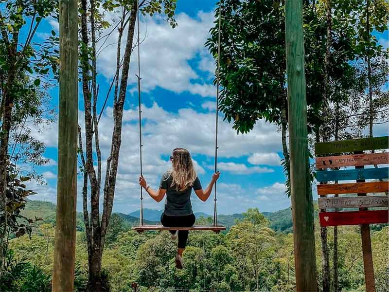 Mulher em balanço com vista panorâmica na Trilha da Natureza, dica do que fazer em Pomerode, SC