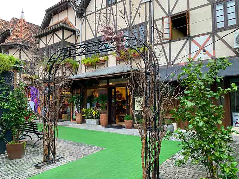 Área externa da Vila Germânica, dica de o que fazer em Blumenau, com construção em estilo enxaimel e tapete verde