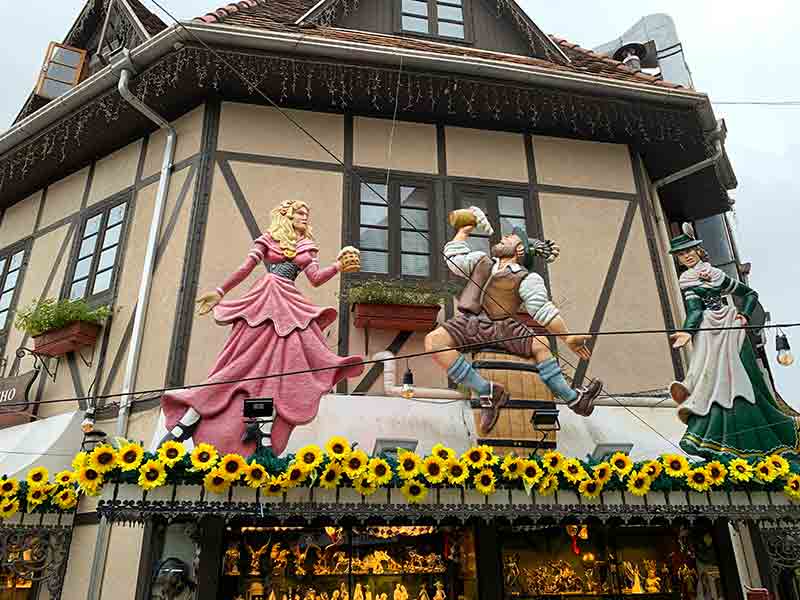 Bonecos com trajes alemãs tomando cerveja em cima de loja na Vila Germânica, dica de o que fazer em Blumenau