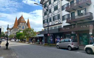 Rua XV de Novembro, em Blumenau, com construções em estilo enxaimel em dia de céu azul com nuvens