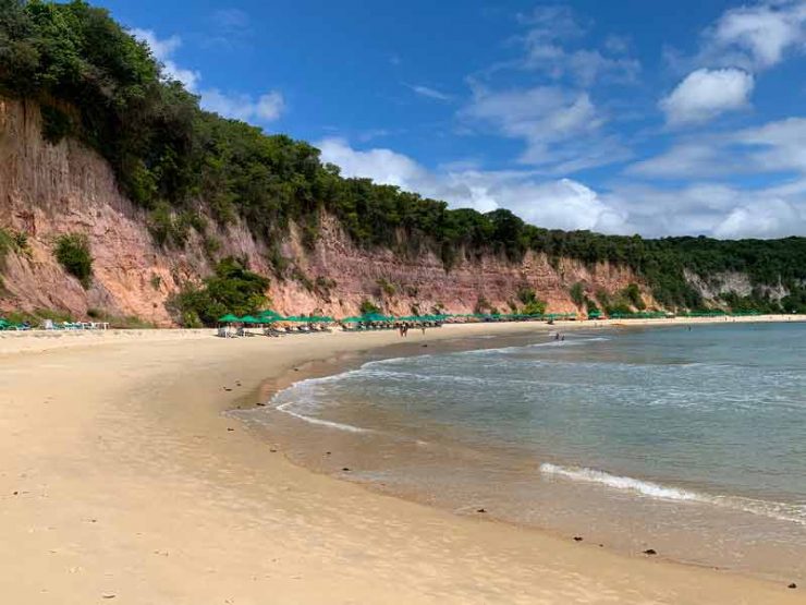 Mar e areia vazios com falésias ao fundo da Baía dos Golfinhos, dica do roteiro em Pipa