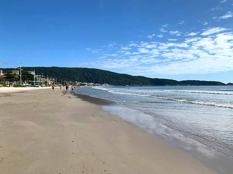 Areia e mar vazios na praia de Bombas em dia de céu azul