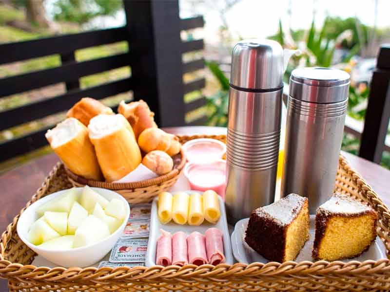 Café da manhã na Pousada dos Ingleses servido em bandeja com frios, pães, café e bolo