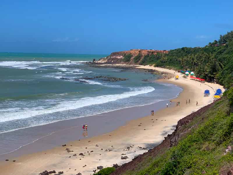 Pessoas caminham pelas areias vazias da Praia do Amor, dica do roteiro em Pipa