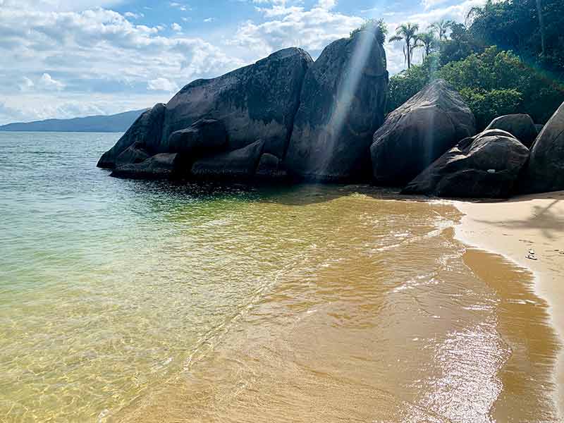 Praia do Cação com mar vazio e raios de sol