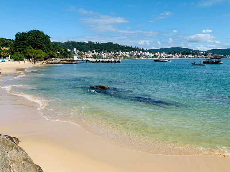 Areia e mar vazios da Praia do Embrulho em dia de céu azul