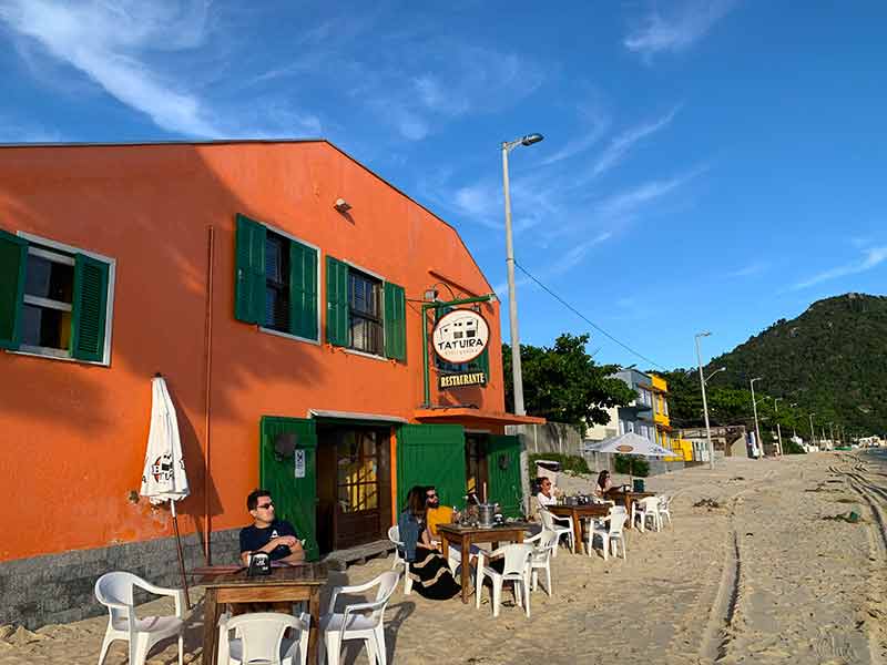 Tatuíra Petisqueira, em Bombinhas, com mesas na areia em dia de céu azul