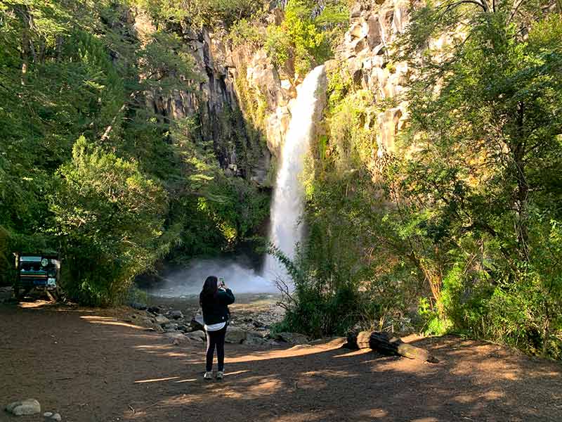 Mulher fotografa queda d'água na cachoeira Salto de la Princesa, na região da Araucanía, no Chile