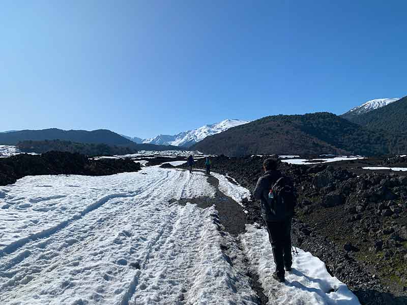 Homem caminha pela neve em dia de céu azul no Parque Nacional de Conguillio, na Araucanía, no Chile