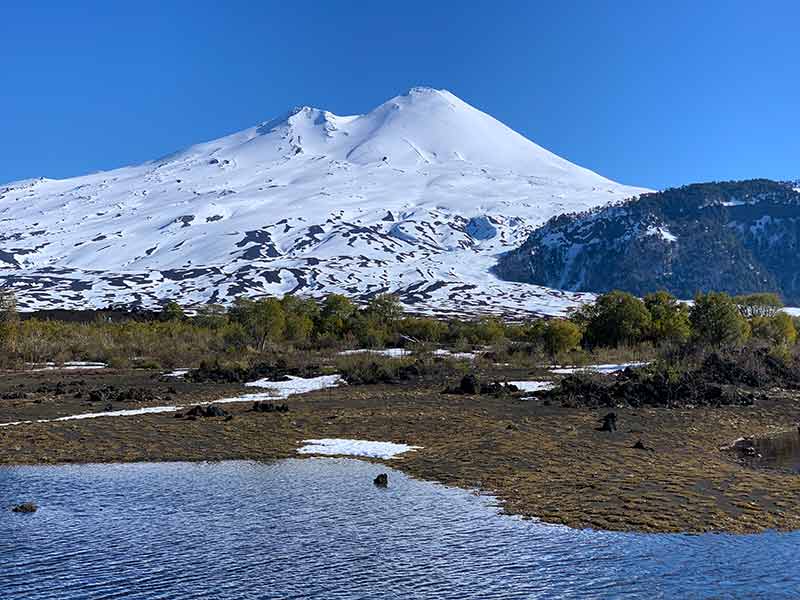 Laguna Verde com vulcão ao fundo e céu azul em Conguillio, na Araucanía, no Chile