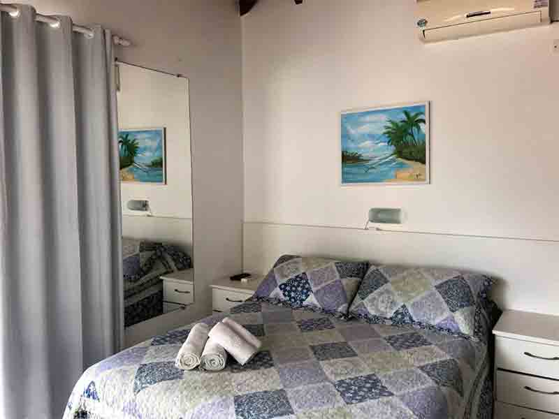 Quarto da Canário Azul, dica entre as pousadas em Bombinhas, com cama de casal e quadro na parede