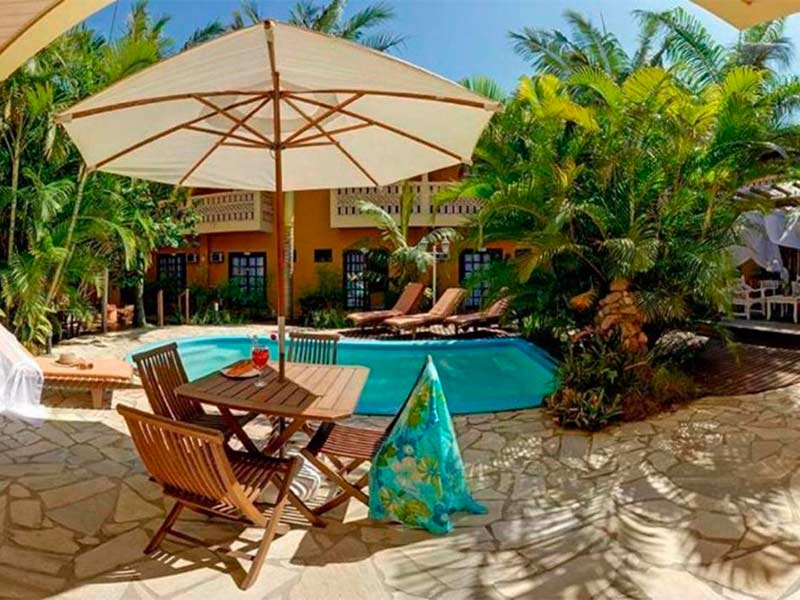 Área da piscina do Dom Capudi, dica entre as pousadas em Bombinhas, com mesa e guarda-sol