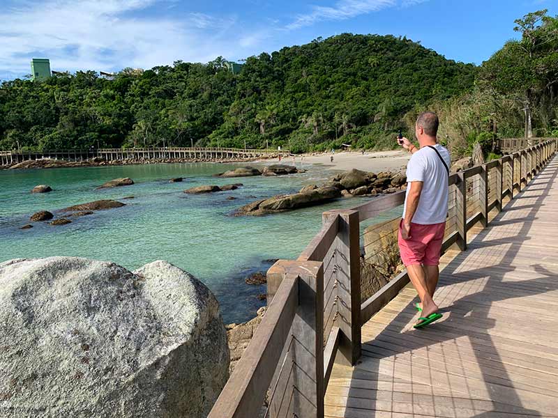 Homem tira foto da praia na Passarela do Ribeiro, em Bombinhas