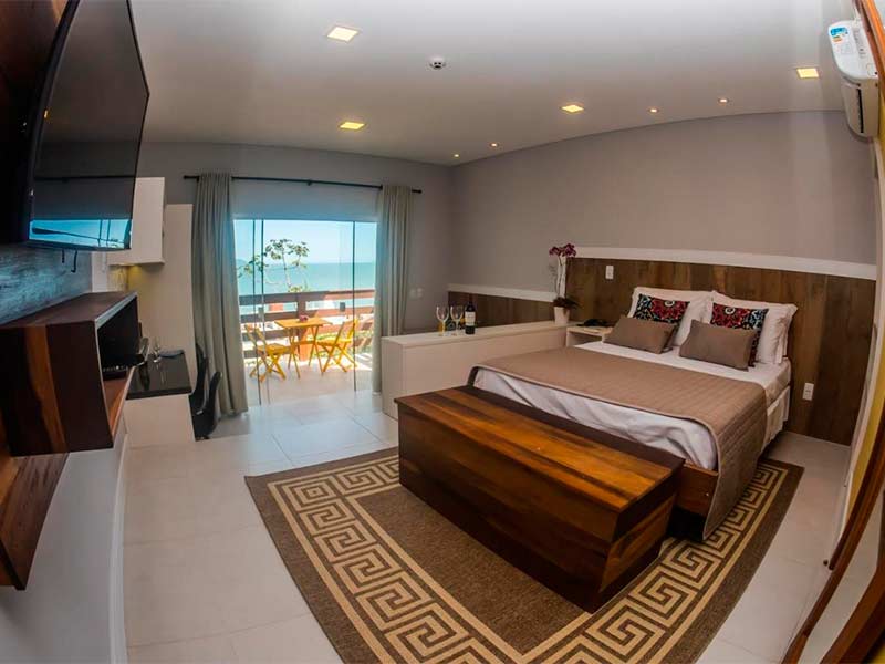 Quarto da Pousada do Arvoredo com cama de casal e varanda com vista para o mar