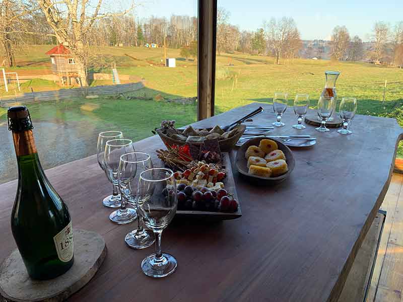 Mesa com vinhos, queijos e bolo com vista para a natureza no Samadhi Eco Resort, na região da Araucanía, no Chile