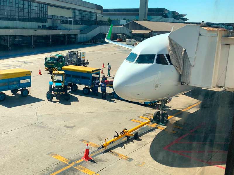 Pessoas colocando malas em avião da Sky Airline no aeroporto de Guarulhos