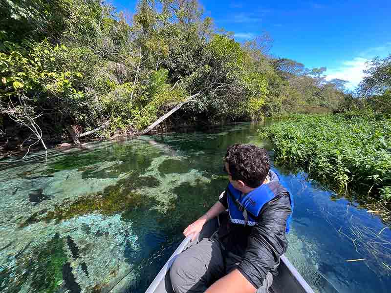 Homem em barco nas águas cristalinas do Rio Sucuri, um dos passeios em Bonito, MS