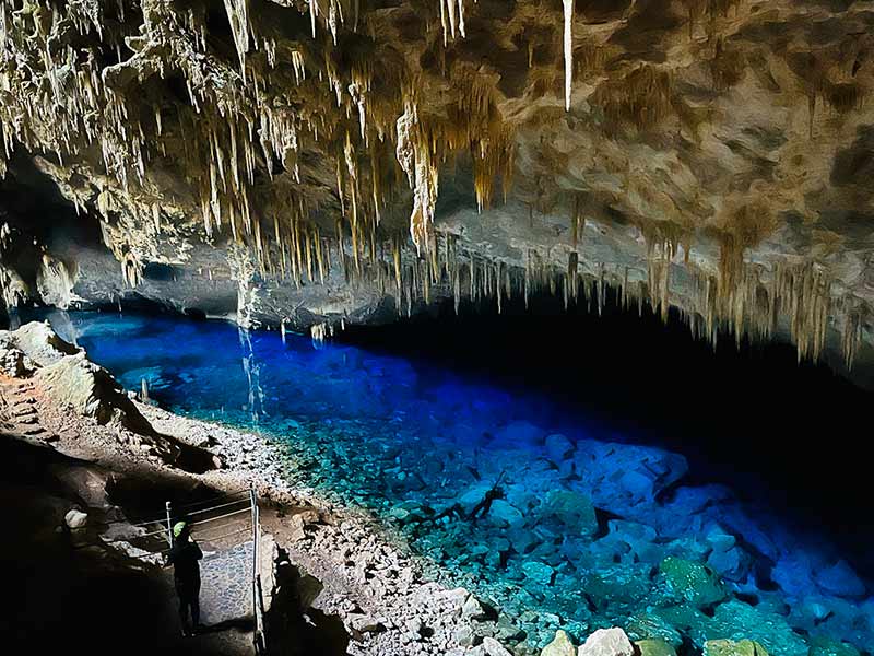 Pessoa dentro da Gruta do Lago Azul, em Bonito, com lago cristalino