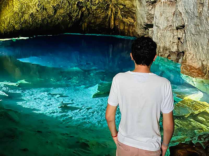 Homem observa lago com cor azulada na Gruta do Mimoso