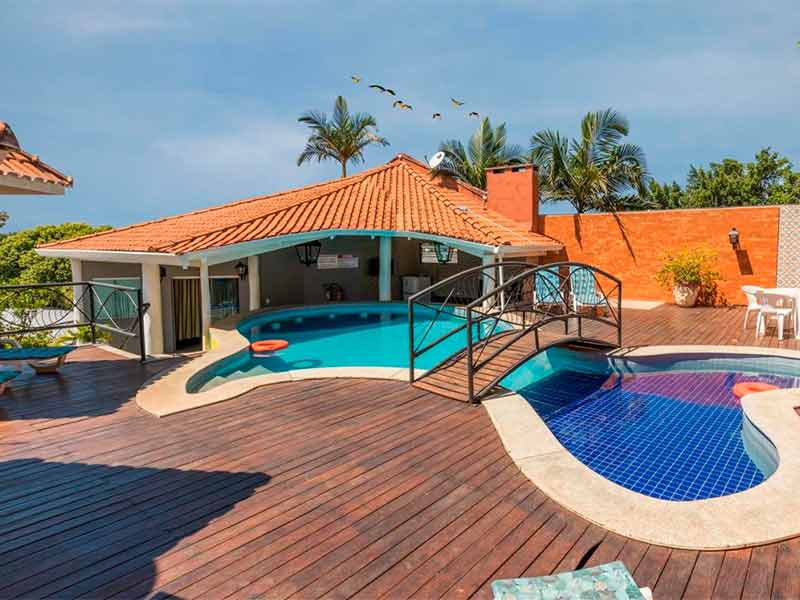 Área da piscina do VOA Hotel Paraíso das Águas com ponte em dia de céu azul