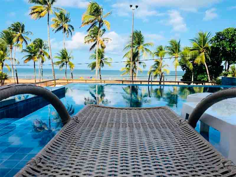 Cadeira e piscinas vazias do Netuanah com vista para a praia