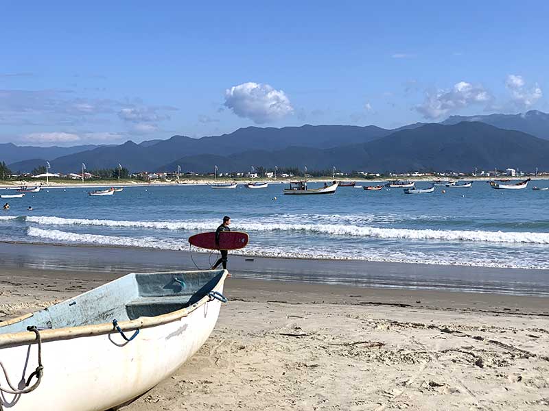 Surfista e barco na Praia da Pinheira em Palhoça, SC