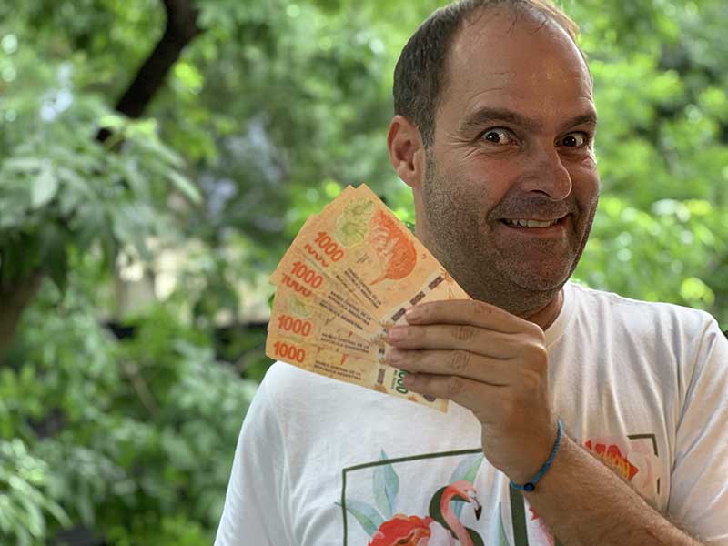 Homem segura notas de pesos retiradas em loja da Western Union na Argentina