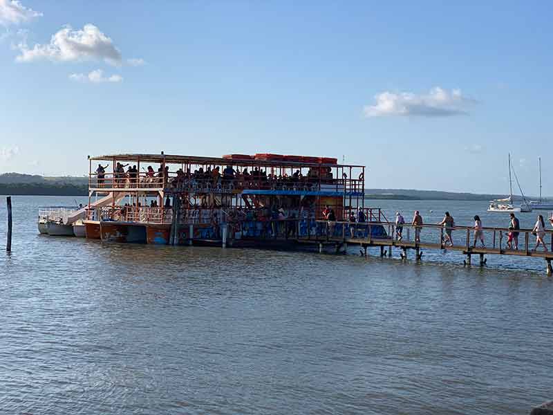 Pessoas entrando em grande catamarã para ver o pôr do sol do Jacaré perto de João Pessoa