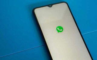 Celular com logo do WhatsApp na tela numa mesa azul
