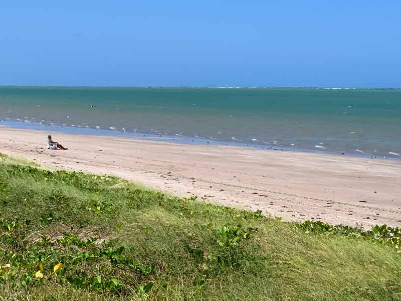 Homem aproveita o sol sozinho na areia de Camboinha, uma das praias de João Pessoa