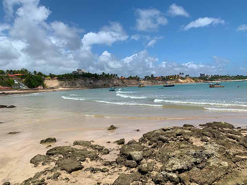 Mar com barcos, falésias e pedras em Carapibus, uma das praias de João Pessoa