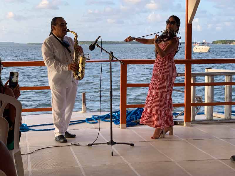 Jurandy do Sax e violinista tocam juntos em barco antes do pôr do sol do Jacaré