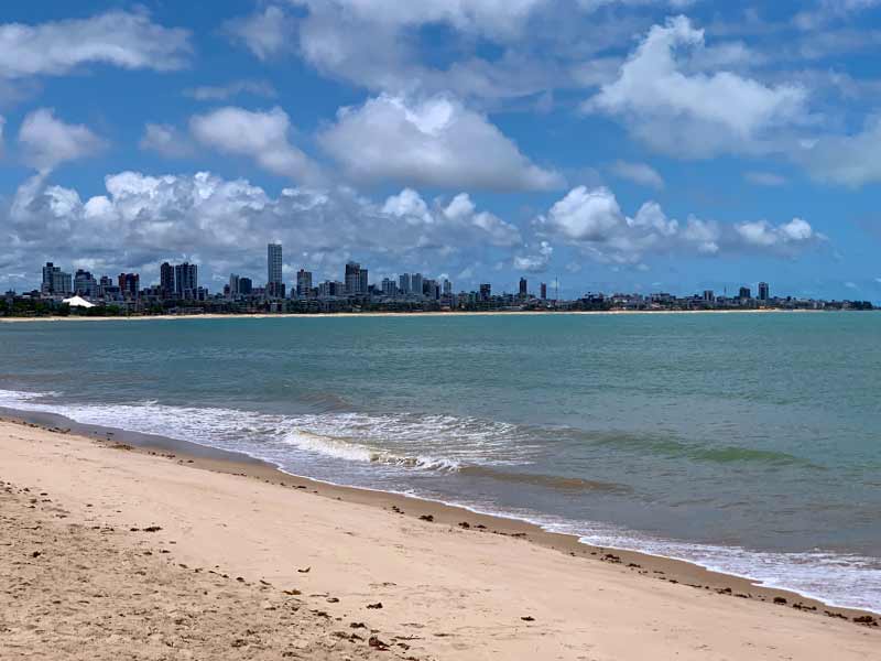 Prédios ao fundo, mar e areia vazia na praia de Manaíra, dica do que fazer em João Pessoa