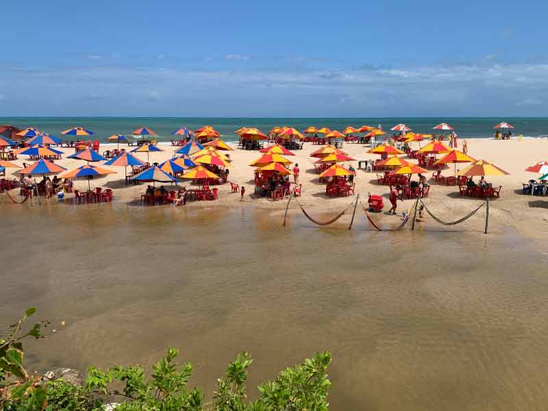 Praia Bela, na Paraíba, com guarda-sóis entre rio e mar