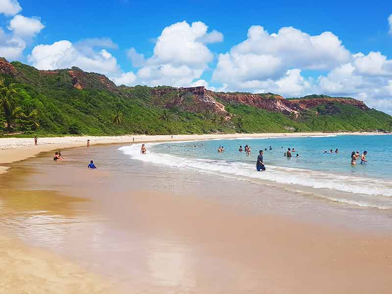 Turistas curtem o mar da Praia de Coqueirinho, perto de João Pessoa, em dia de poucas nuvens