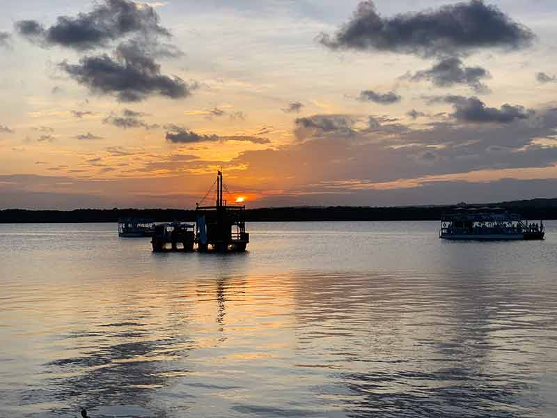 Pôr do sol na Praia do Jacaré com barco navegando no mar