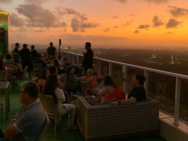 Pessoas curtem o entardecer de João Pessoa sentadas nas mesas do Sky Bar